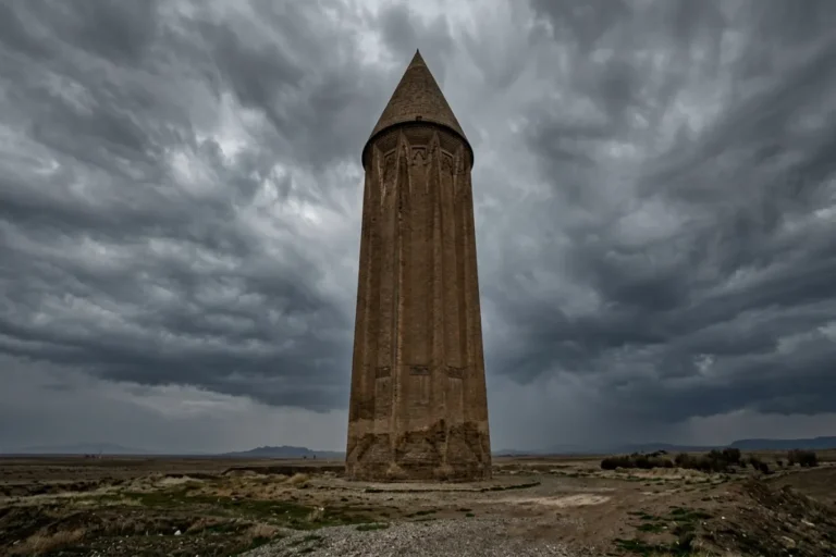 نمای نزدیک از برج آجری گنبد کاووس زیر آسمان ابری
